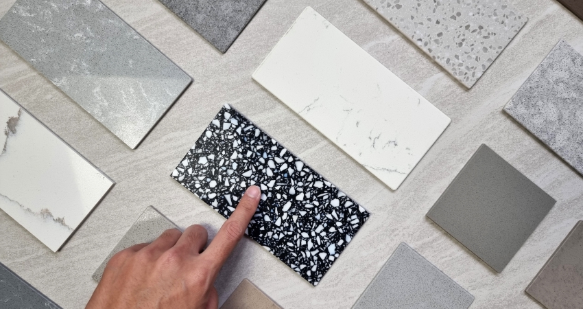 A person is pointing at a variety of marble tiles.