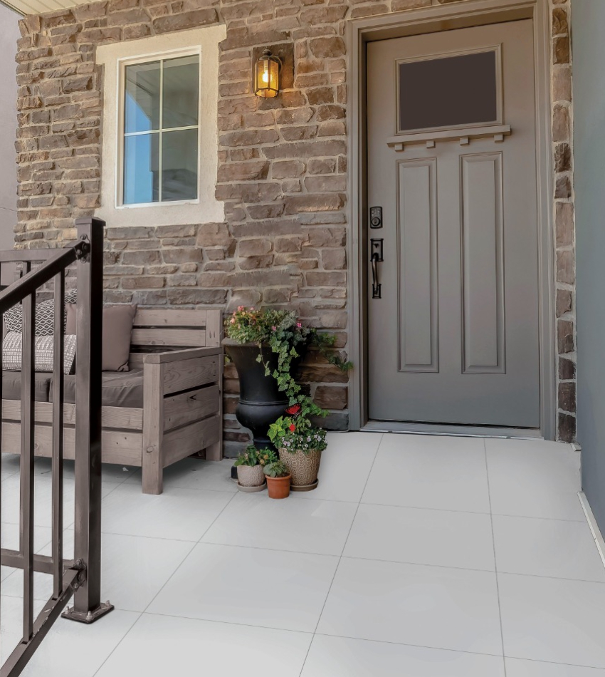 A white tiled front porch with a bench and railing.