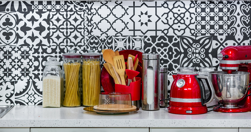 A black and white kitchen with a red mixer and utensils.