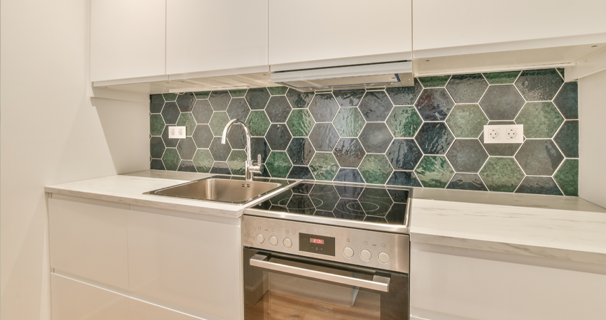 A kitchen with a green tiled backsplash.