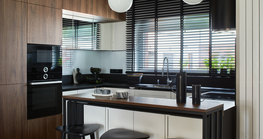 A modern kitchen with wooden cabinets and black stools.