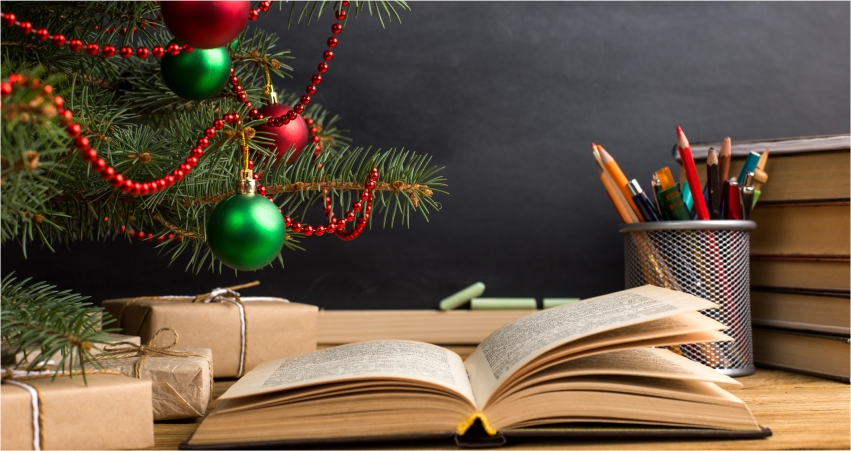 A book on a table next to a christmas tree.