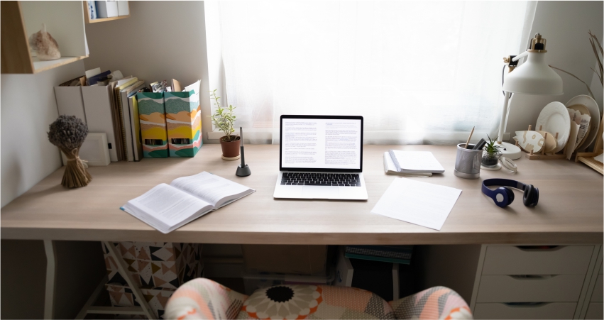 A desk with a laptop and books on it.