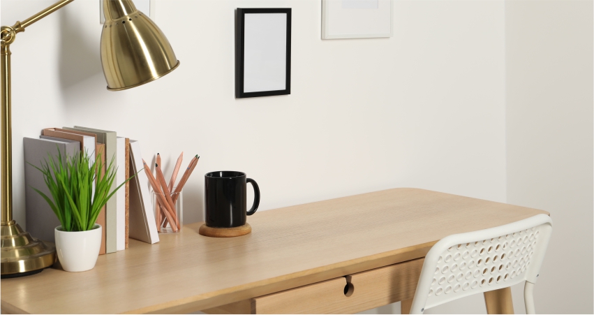 A desk with a lamp and a plant on it.