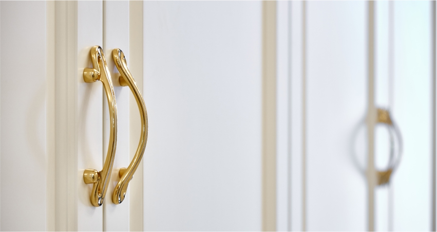 Elegant gold door handle on a white door with a blurred background.