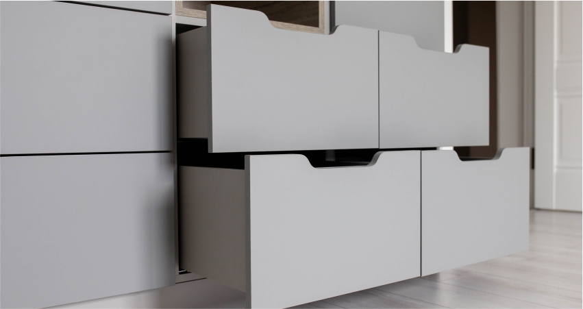 A close-up of modern white storage drawers with a handleless design.