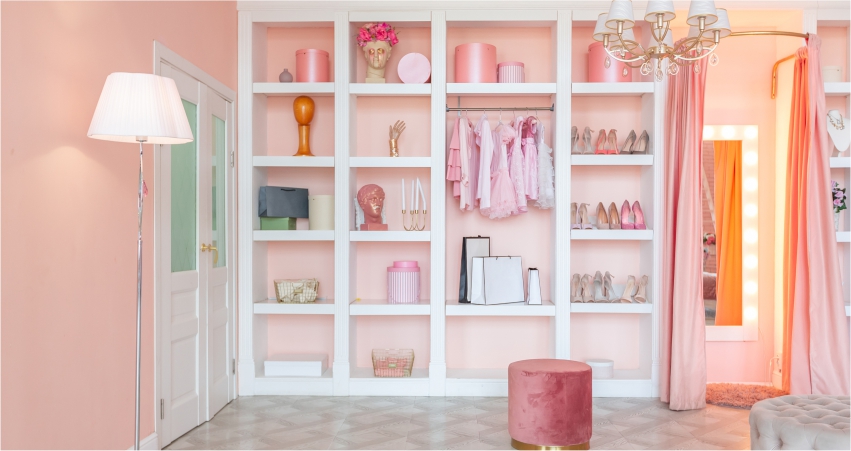 A pink-themed dressing room with neatly organized shelves, clothes, and accessories.