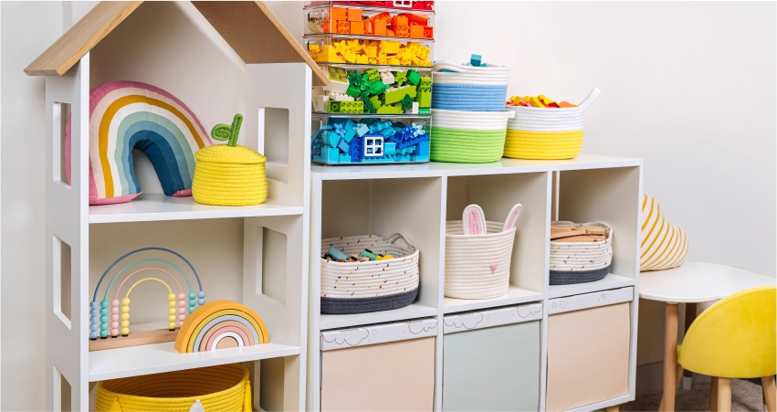 A neatly organized children's play area with toys and colorful storage baskets on white shelves.