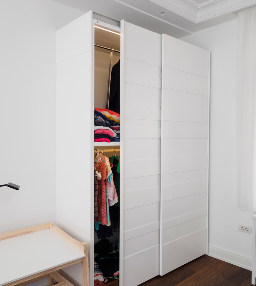 A partially open white wardrobe revealing clothes and accessories inside.