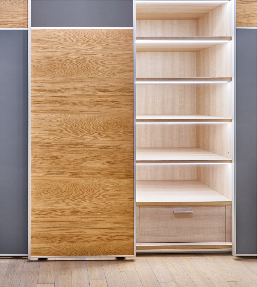 Modern wardrobe with sliding doors, one open to reveal empty shelves and a single drawer.