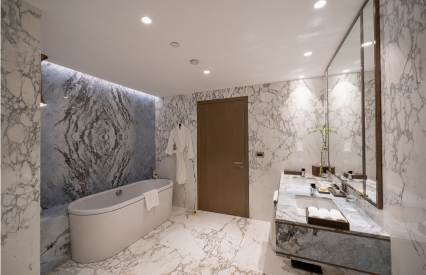 Modern bathroom with stone look wall tiles and bathtub 