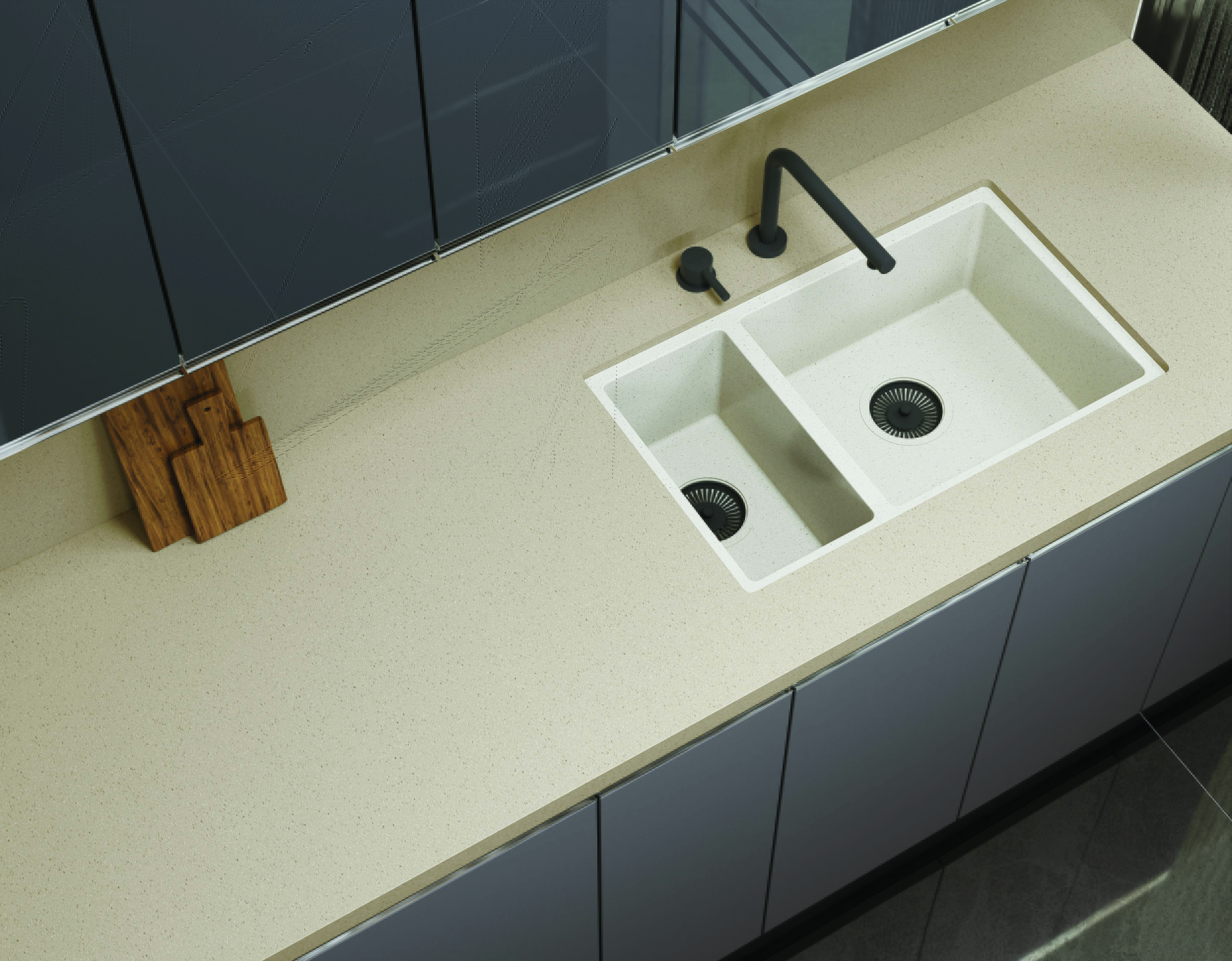 A modern kitchen counter with beige stone tiles, double sink, and black fixtures
